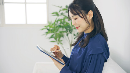 室内でタブレットPCを使う女性 © metamorworks