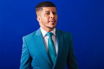 Brazilian black man, dressed in a suit and blue tie. business man. winking at camera