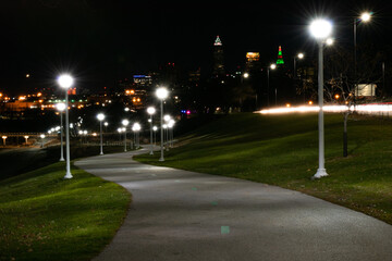 Nighttime park path with Cleveland city background and streetlamps.