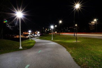 Long exposure nighttime park path with city background and streetlamps.