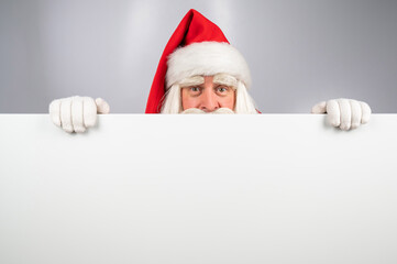 Santa Claus peeks out from behind an ad on a white background. Merry Christmas.