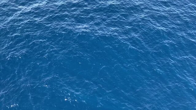 Aerial View of a Crystal clear sea water texture. Blue ocean wave. Beautiful aquatic view with sunbeams shining and creating god rays