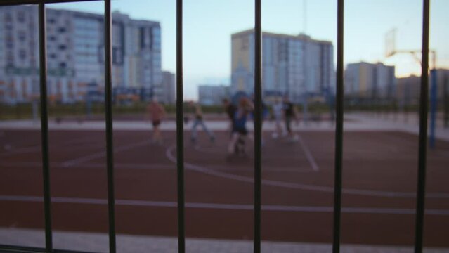 background of Russian men play basketball in the evening at sunset, fence basketball game, no focus