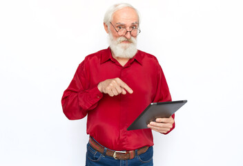 Happy senior man pointing at tablet computer. Pleased Caucasian male model with gray hair and beard in red shirt and glasses looking at camera, smiling. Modern technology, advertising concept