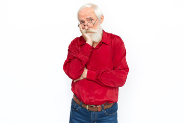 Bored senior man leaning on hand. Sleepy Caucasian male model with gray hair and beard in red shirt and glasses looking at camera with raised eyebrows. Boredom, apathy concept