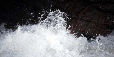 Water Drops after splash. Splashing of the mountain river against the dark rocks. Splashes of clear...