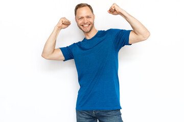 Happy Caucasian man celebrating success, raising fists. Bearded man smiling at camera, enjoying victory or winning while standing on white background. Success, achievement, excitement concept