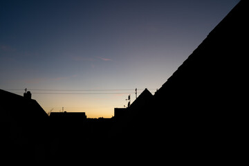Obraz premium Silhouette of house roofs on a summer evening as the sun goes down