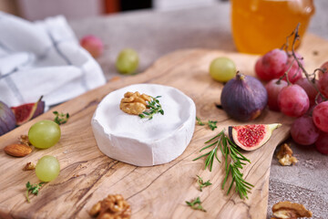 Camembert or brie cheese on wooden cutting board at domestic kitchen