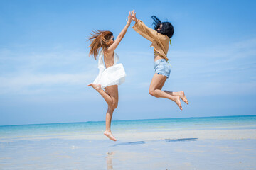 Fototapeta premium Two attractive girls jumping on the beach,Having Fun,Summer Lifestyle.