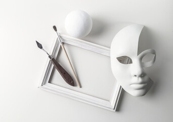 Black and white mass still life: a mask on a white background, a picture frame, abstraction