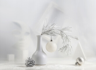 Monochrome Christmas still life: pine branch in a white vase, Christmas decorations, abstract