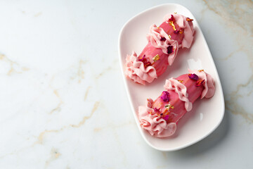 Obraz na płótnie Canvas Eclair dessert with pink icing on white table