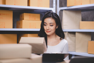 Fototapeta na wymiar Businesswoman is looking and checking a parcel box. Freelancers or saleswoman, is checking production packaging. Entrepreneur SME working with parcel box at home. Concept online delivery.
