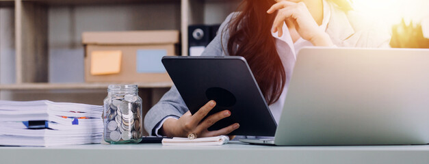Young business woman sitting in office at table and using smartphone. On desk is laptop and tablet computer, on screen charts and graphs. Woman analyzing data. Student learning online.