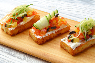 Delicious vegetable bruschetta slices on wooden board