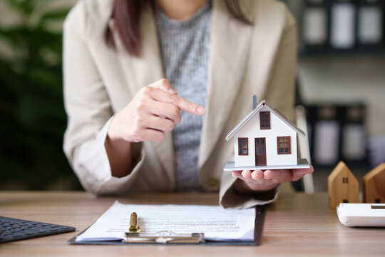 Female Real Estate Agent Offers Home Equity Loans To Clients With Loan Calculations And Home Sales Contracts In The Office. Real Estate And Insurance Buying Savings Concept