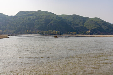 Obraz premium Beautiful scenery of river flowing water early in the morning with a green hills in background