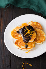 pancakes with chocolate glaze and candied orange on a serving plate