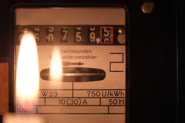 Vintage electric meter with candle light in front. Checking the consumption of electicity. Concept...