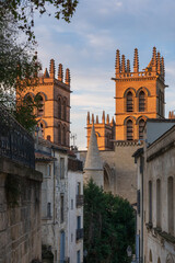 Fototapeta na wymiar Landscape view at sunset of ancient historic landmark St Pierre or St Peter's cathedral bell towers through narrow street, Montpellier, France