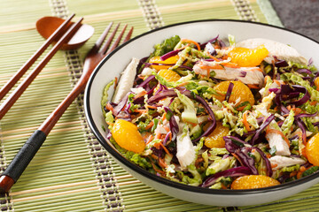 Chinese Chicken Salad made with mandarin, cabbage, carrots, green onions and chicken with Asian Dressing close up in the bowl on the table. Horizontal