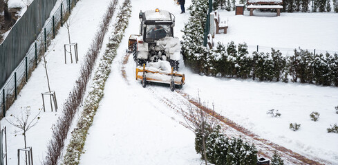 Tractor cleans snow with a brush in the city