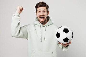Young excited happy man 20s fan wearing mint hoody do winner gesture cheer up support football...
