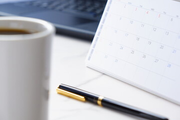 カレンダーとコーヒーのマグカップのイメージ