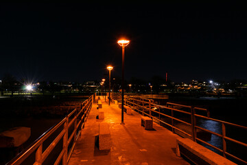 Pier at nighttime with city lights background.