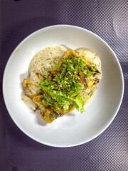 Delicious homemade vegan omelet prepared with seasonal vegetables and served with fresh lettuce in white plate.