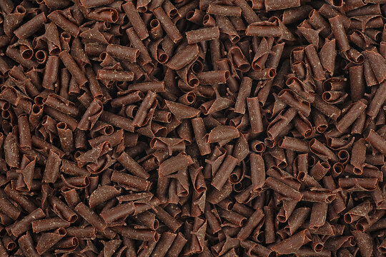 Pile of chocolate curls as background. Chocolate flakes. Grated chocolate.