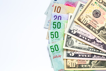 Maldives banknotes and dollar banknotes arranged in a chaotic manner. Group of money maldives and dollar banknotes on a white background and space for text. Exchange money, travel concept.