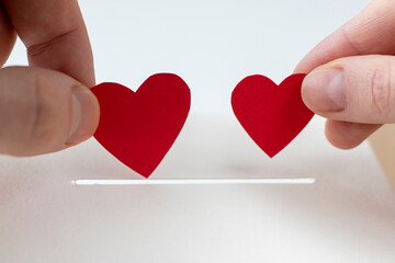 The concept of charity, love, donation and helping hands. A woman and a man hand puts the heart in...