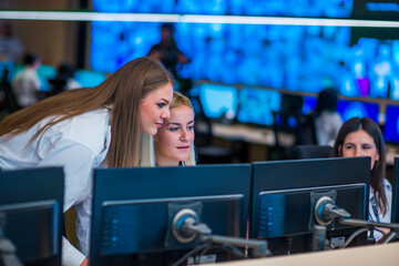 Female security guards working in surveillance room, monitoring cctv and discussing.