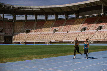 Attractive friends jogging at the empty stadium