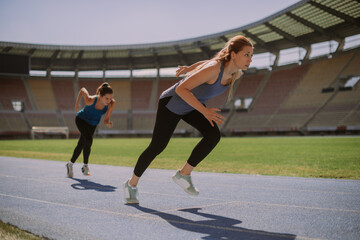 Fototapeta premium Pretty girls running on a blue sports track