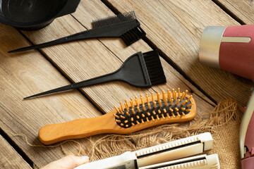 Hairdryer, leveling tongs and combs with brushes lie on a wooden table, a hairdressing set lies on a table in a beauty salon, hair care, stylist