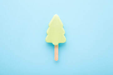 Light green spruce shape ice cream with pistachio or mint taste on stick. Light blue table...