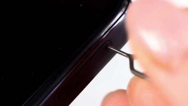 Woman hands pulling out the phone sim card tray from the smartphone with the help of edgector close up