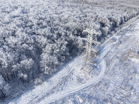 High-voltage transmission tower in the winter forest.