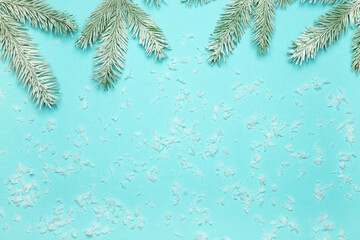 Snow-covered fir branches and lying artificial snow on a blue background. The concept of Christmas and New Year.