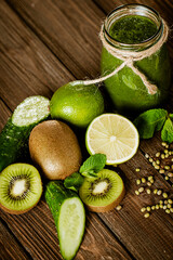 Blended green smoothie with ingredients on the wooden table. Green cocktail. Healthy food 