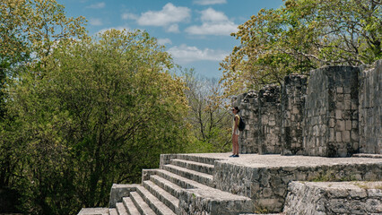 Fototapeta premium Woman staring in front of the ruins of the mayas pyramids at Edzna, Yucatan 