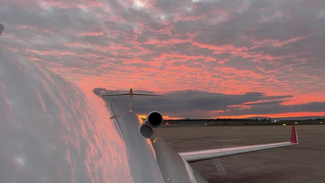 Extraordinary red sky at sunset reflected on the upper juselage of a jet while other plane is landing at the back. Real colors.
