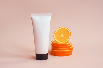 Mockup pink squeeze bottle cosmetic tube with screw black cap and orange slices on pink background. Lotion, moisturizer, balsam, hand cream, gel, skincare with vitamin c. Mock-up, front view - obrazy, fototapety, plakaty