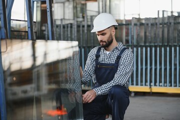 Portrait of workerin coverall working with PVC window at factory
