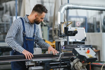 Worker in uniform working on machine in PVC shop indoor