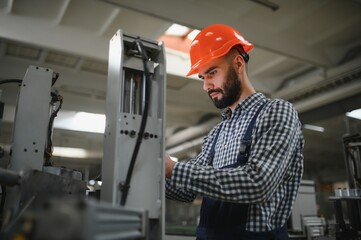 Portrait of factory worker in protective equipment in production hall.