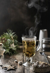 A glass of green tea with steaming and Christmas decoration on wooden table. Winter time. Text space